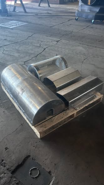 Assorted fabricated stainless components staged on a wooden pallet